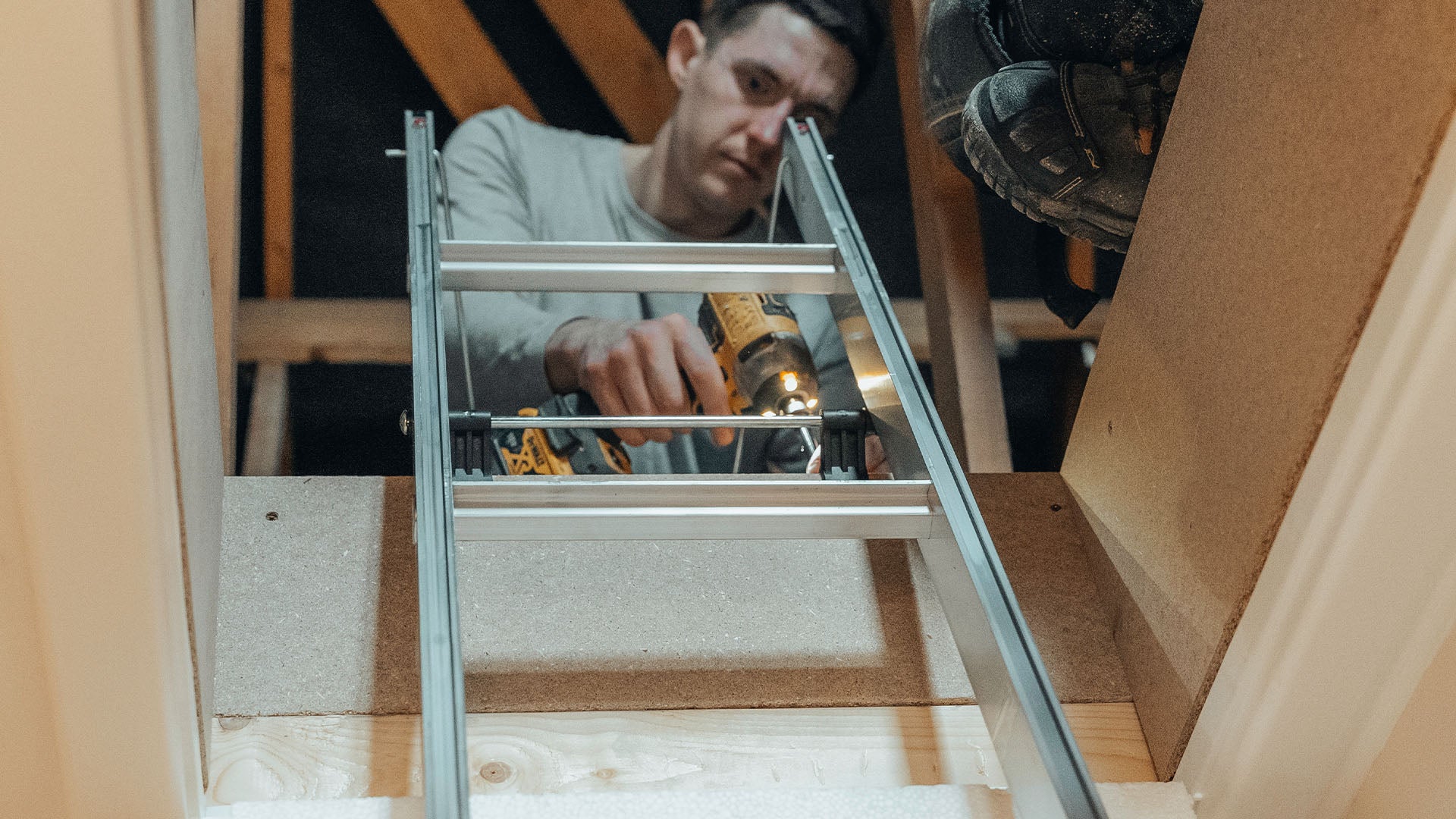 Loft installer screwing in a loft ladder — Loft-Trac