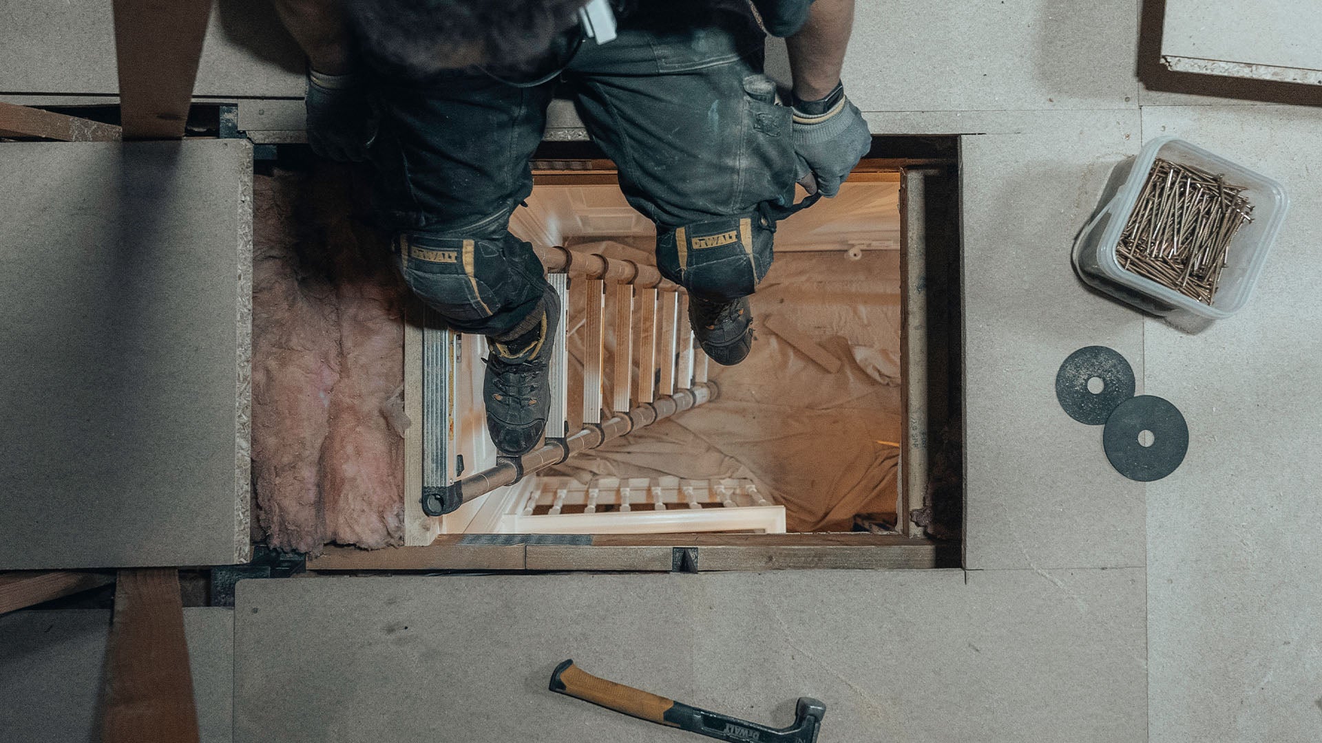 Loft installer sitting in the loft hatch — Loft-Trac