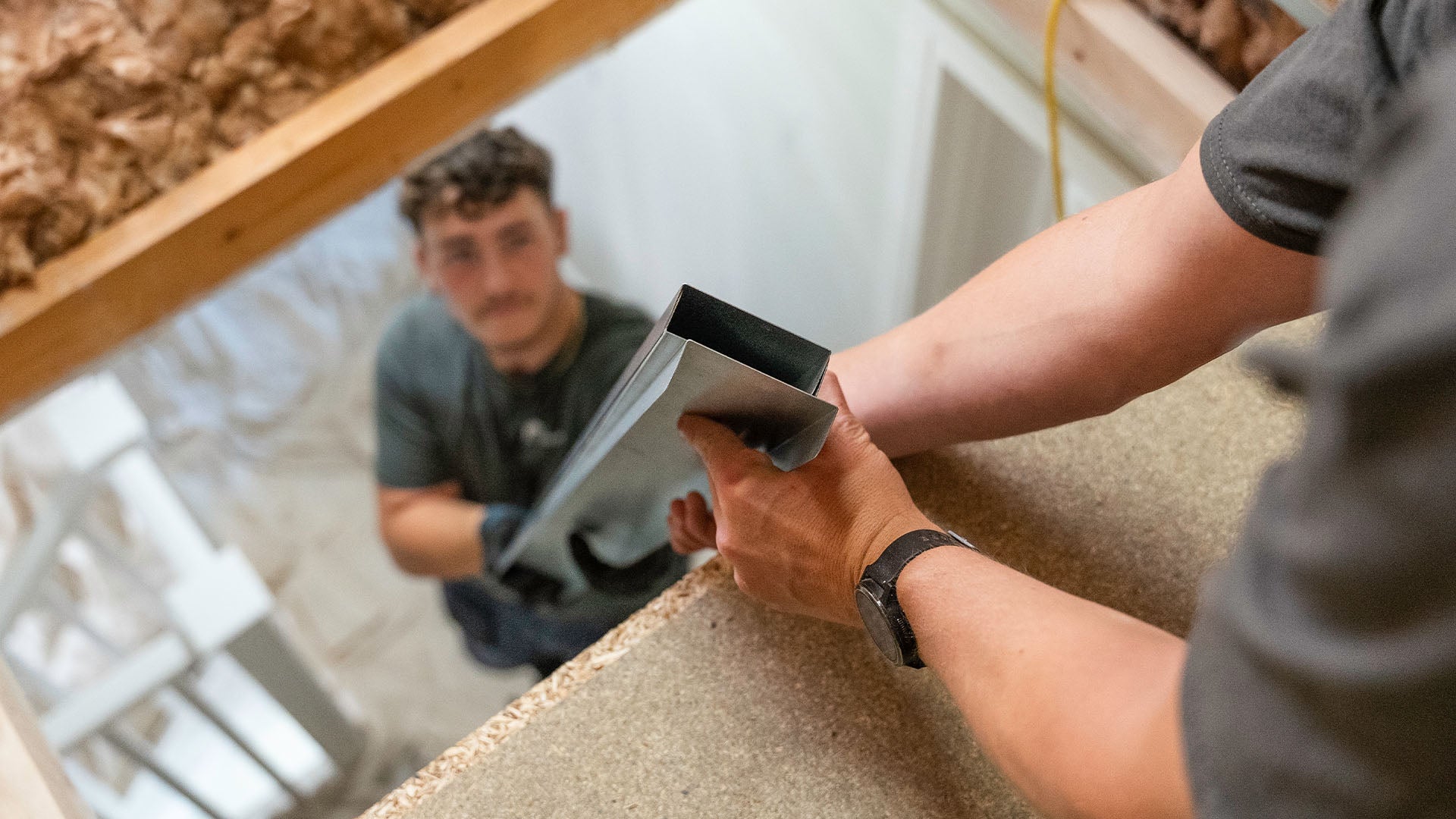 Two installers passing Loft-Trac Cross Beams — Loft-Trac